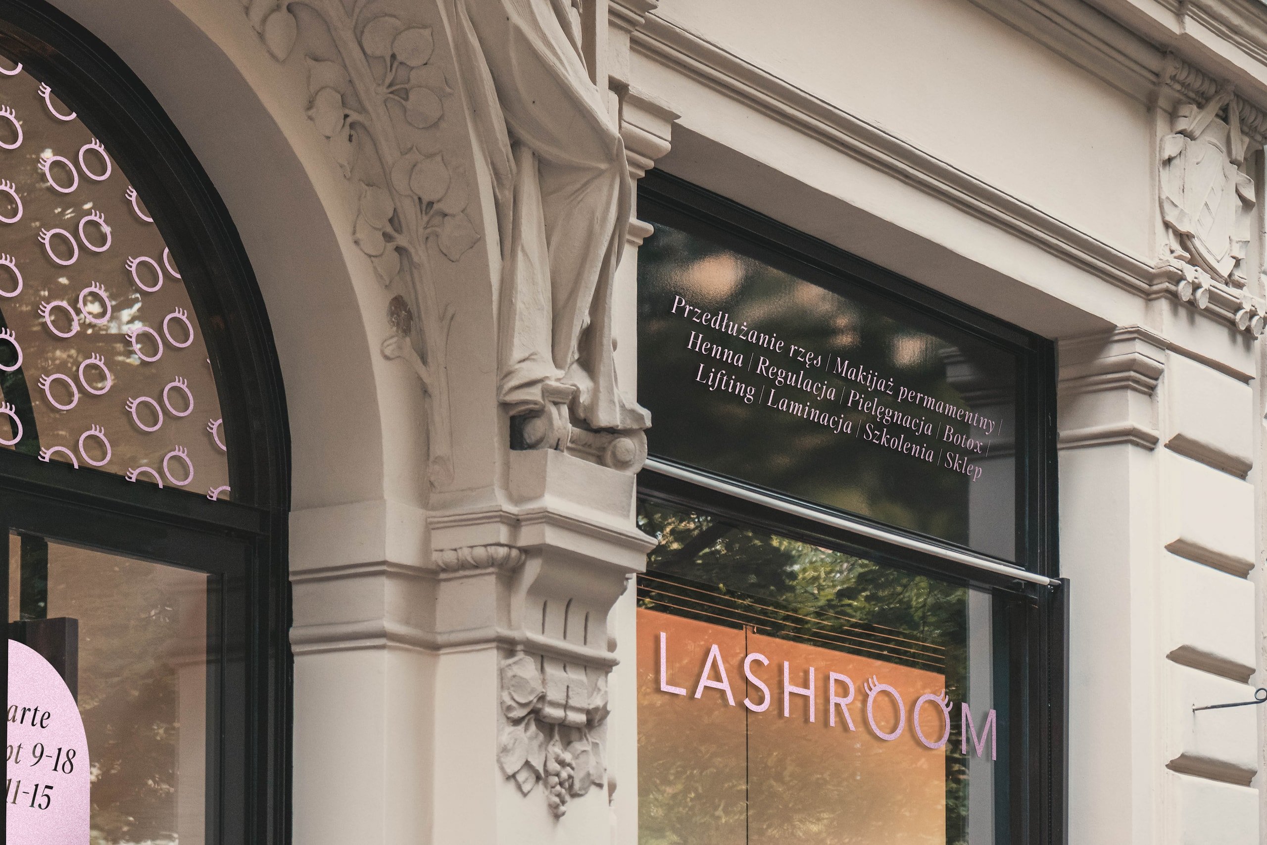 Witryna salonu Lashroom w kamienicy z oklejeniem z listą usług i podświetlanym napisem LASHROOM oraz motywem oczu z rzęsami